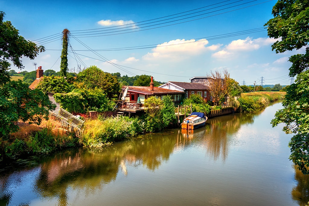 Riverside homes and boat beneath a blue sky